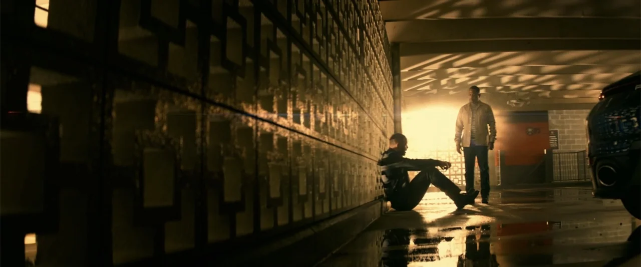 Bad Boys for Life (2020) movie still: wide — A concrete parking garage interior features a geometric breeze block wall on the left side. One man…