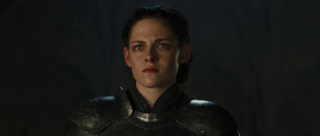 Snow White and The Huntsman (2012) movie still: closeup — A dark, undefined space serves as the backdrop for a figure in armor. The subject looks…