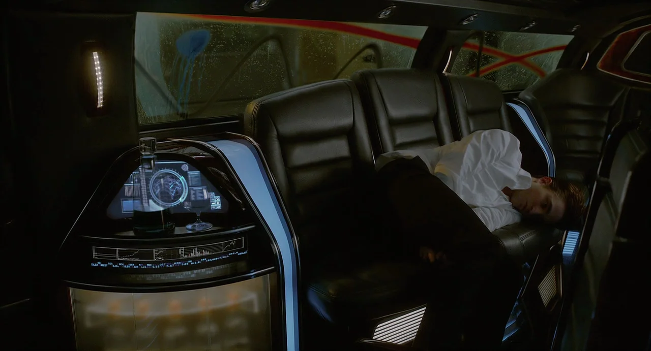 Cosmopolis (2012) movie still: medium — The interior of a high-tech limousine features black leather seating and digital instrumentation. A man in a…