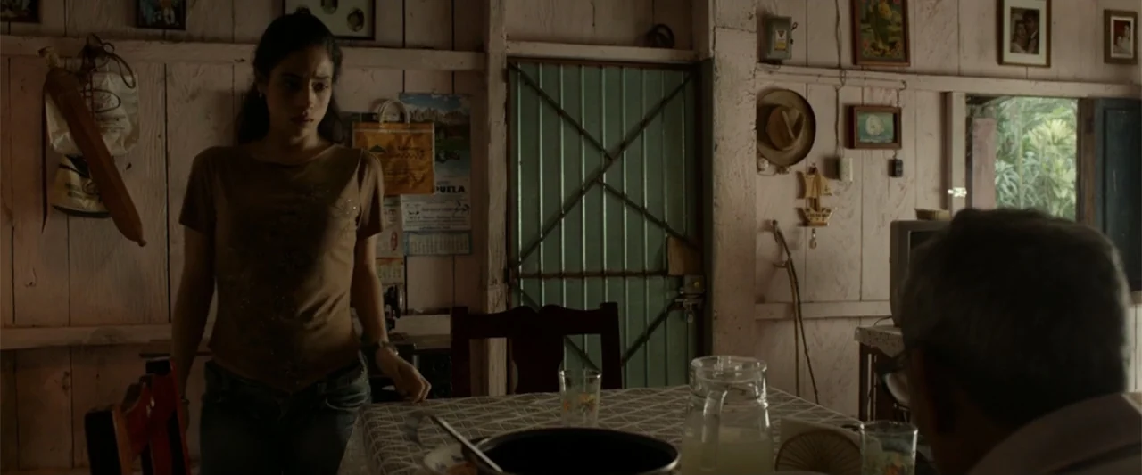 I Dream in Another Language (2017) movie still: medium — A rustic domestic interior has light-colored wooden plank walls decorated with numerous…