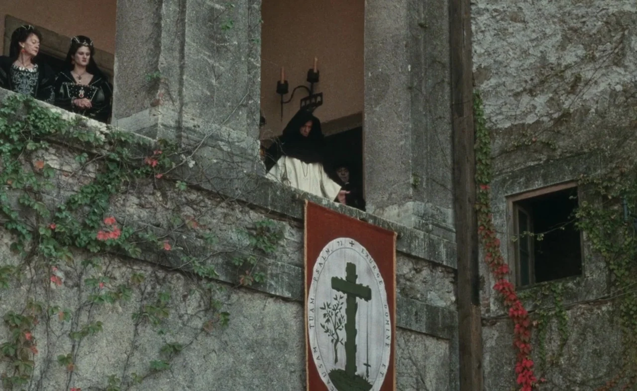 The Pit and The Pendulum (1991) movie still: wide — A stone balcony of an old building is covered with vines and red leaves. A central robed figure…