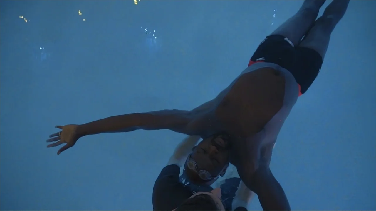 A Film Called Blacks Can't Swim (My Journey My Story) (2020) movie still: medium — A dark blue swimming pool environment with clear water and tiling…