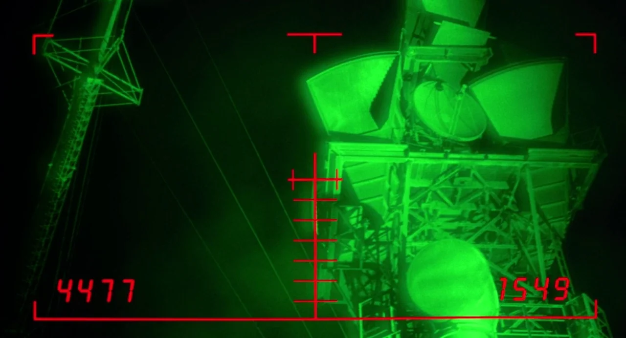 Bad Boys (1995) movie still: wide — A tall industrial communication tower is observed through night vision technology at night. The metal framework…
