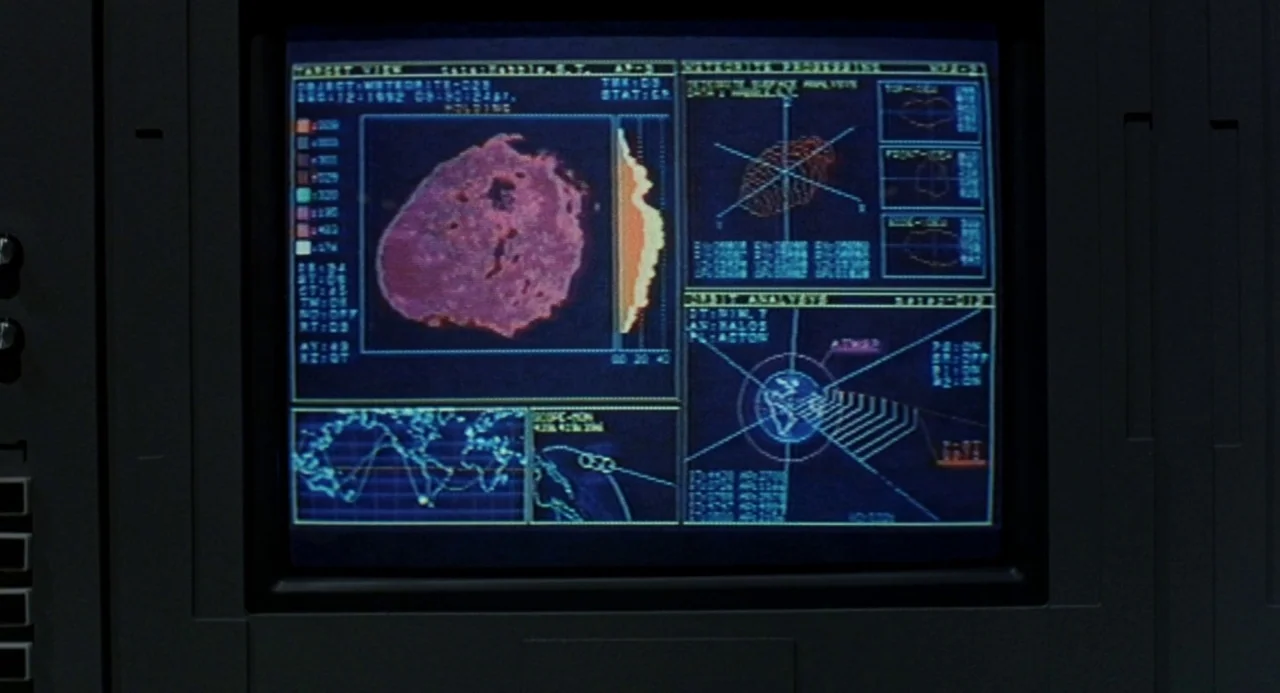 Godzilla and Mothra: The Battle for Earth (1992) movie still: closeup — A dark computer monitor displays various charts, a world map, and meteorite…