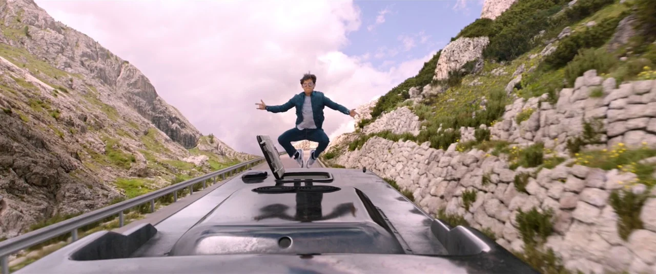 Spider-Man: Far From Home (2019) movie still: wide — A narrow mountain road winds through a rocky landscape with sparse green vegetation. A young…