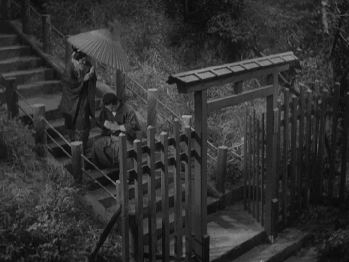 Sanshiro Sugata (1943) movie still: wide — An outdoor stone staircase winds through a wooded area with a traditional wooden gate. A woman stands…
