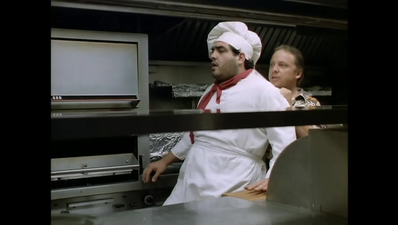 The Awakening (1995) movie still: medium — A professional kitchen features stainless steel ovens and metallic workstations under bright overhead…