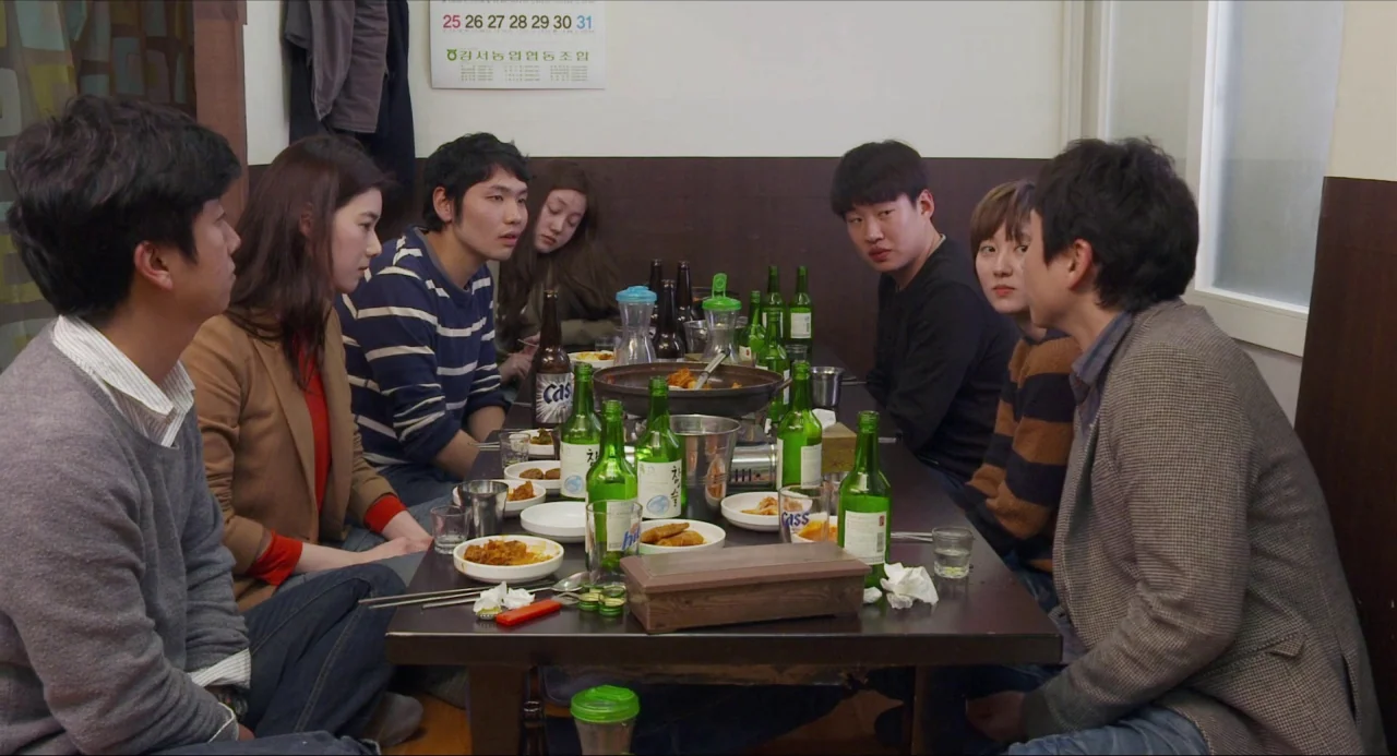 Nobody’s Daughter Haewon (2013) movie still: medium — A group of seven people are gathered around a rectangular table at a restaurant. They are…