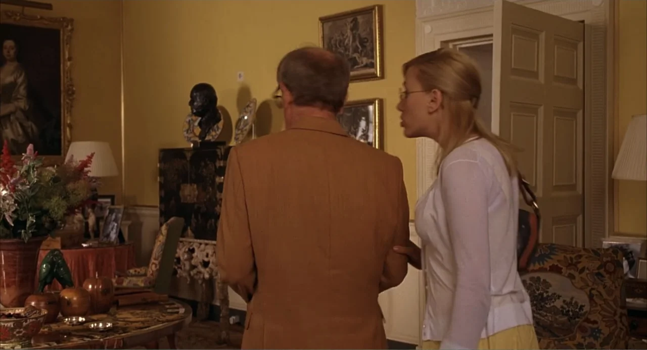 Scoop (2024) movie still: medium — An opulent room with yellow walls features ornate artwork, traditional decor, and antique furniture pieces. A…