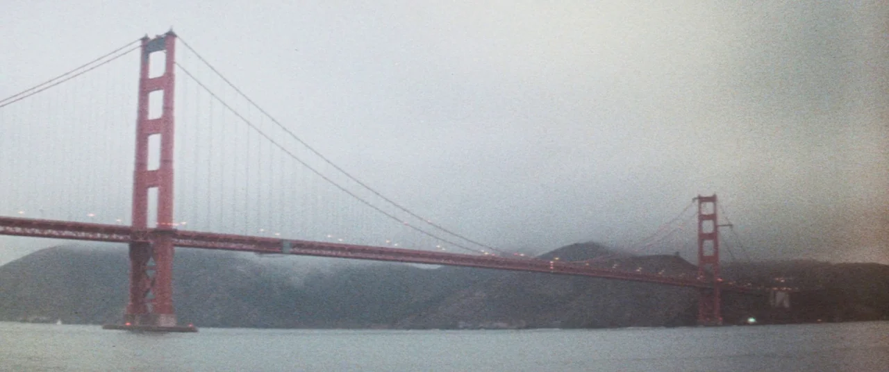 Death Game (1977) movie still: establishing — The Golden Gate Bridge spans across a wide body of water under heavy fog. Dense grey mist surrounds…