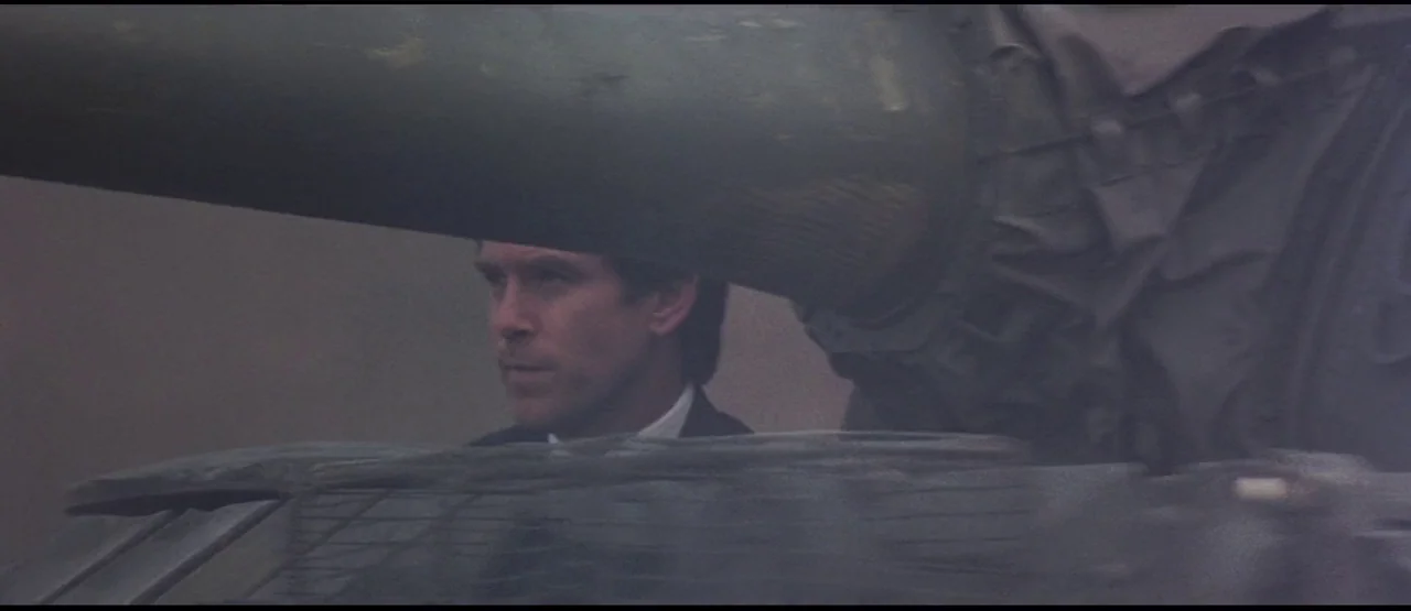 GoldenEye (1995) movie still: medium — A man peers out from the open hatch of a heavy olive-drab tank. The large barrel of the tank cannon looms…
