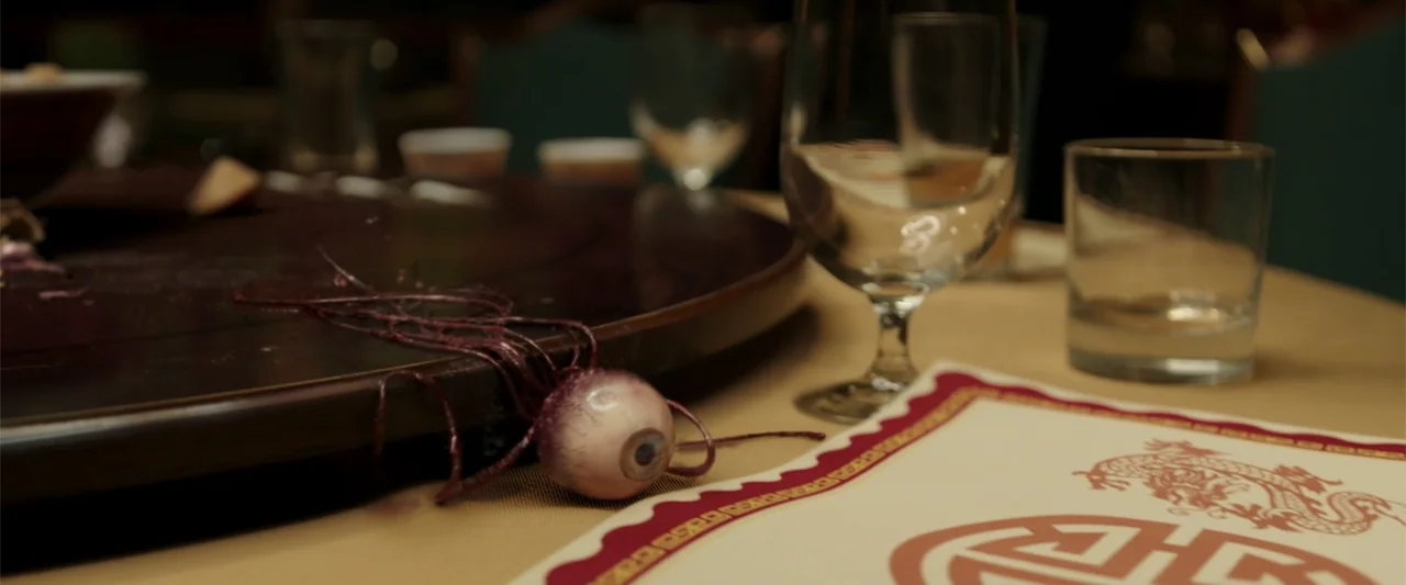 K.G.F: Chapter 2 (2022) movie still: closeup — A close-up shot focuses on a dark wooden lazy susan atop a restaurant dining table. A single…