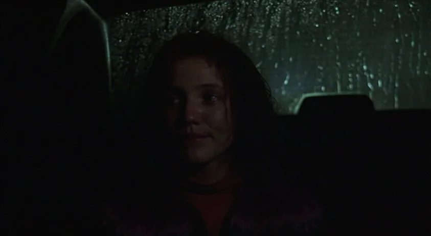 Being John Malkovich (1999) movie still: closeup — A woman sits inside a car at night during a heavy rainstorm. Rain streaks across the rear window…