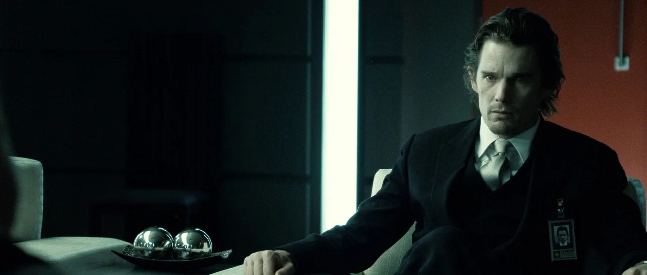 Daybreakers (2009) movie still: medium — A modern office environment features dark walls, an orange accent panel, and minimalist furniture. A man in…