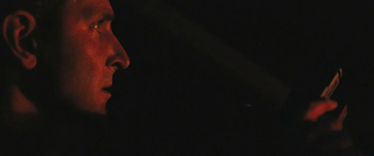 The Place Beyond The Pines (2012) movie still: closeup — The interior of a vehicle is shrouded in darkness during the night. A man sits in the…