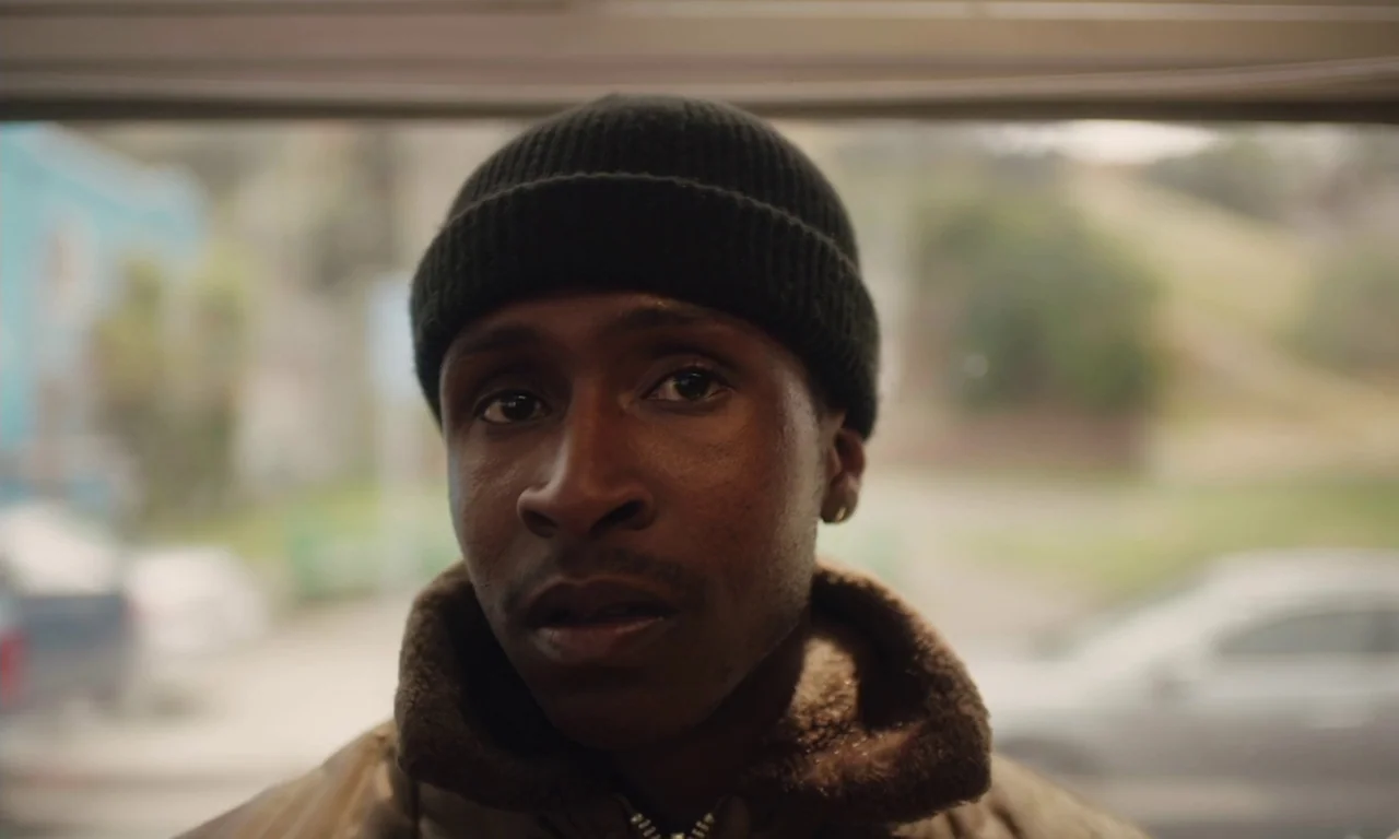 The Last Black Man in San Francisco (2019) movie still: closeup — A man stands in a brightly lit exterior doorway against a blurred residential…