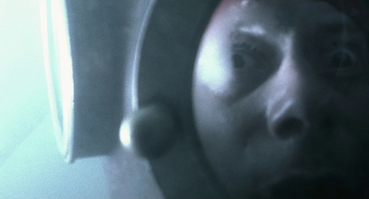 The Diving Bell and the Butterfly (2007) movie still: closeup — A dark, cramped interior of a metallic deep-sea diving helmet. A person looks out…