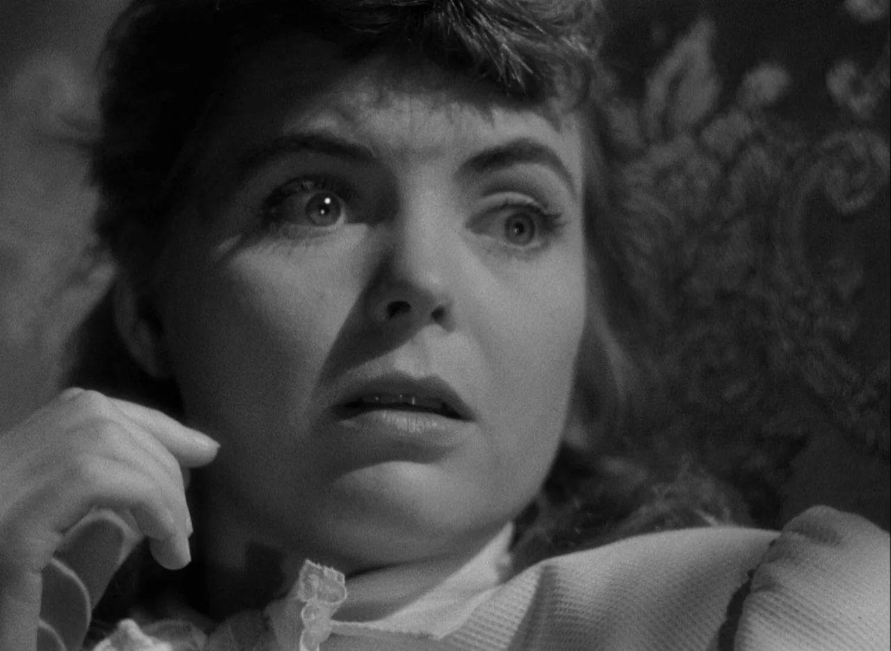 The Spiral Staircase (1946) movie still: closeup — A close-up view of a young woman sitting in a dimly lit room. She looks toward the side of the…