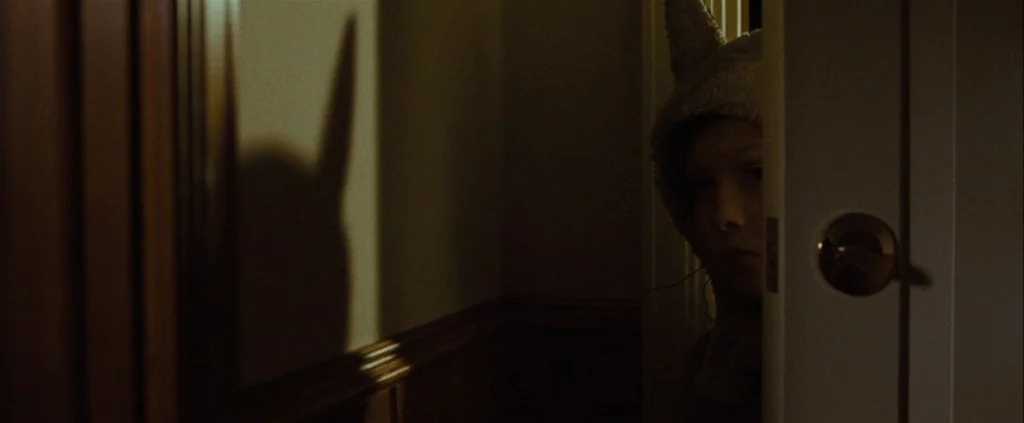 Where The Wild Things Are (2009) movie still: closeup — A dark, wood-paneled hallway is partially obscured by a partially opened white door. A child…