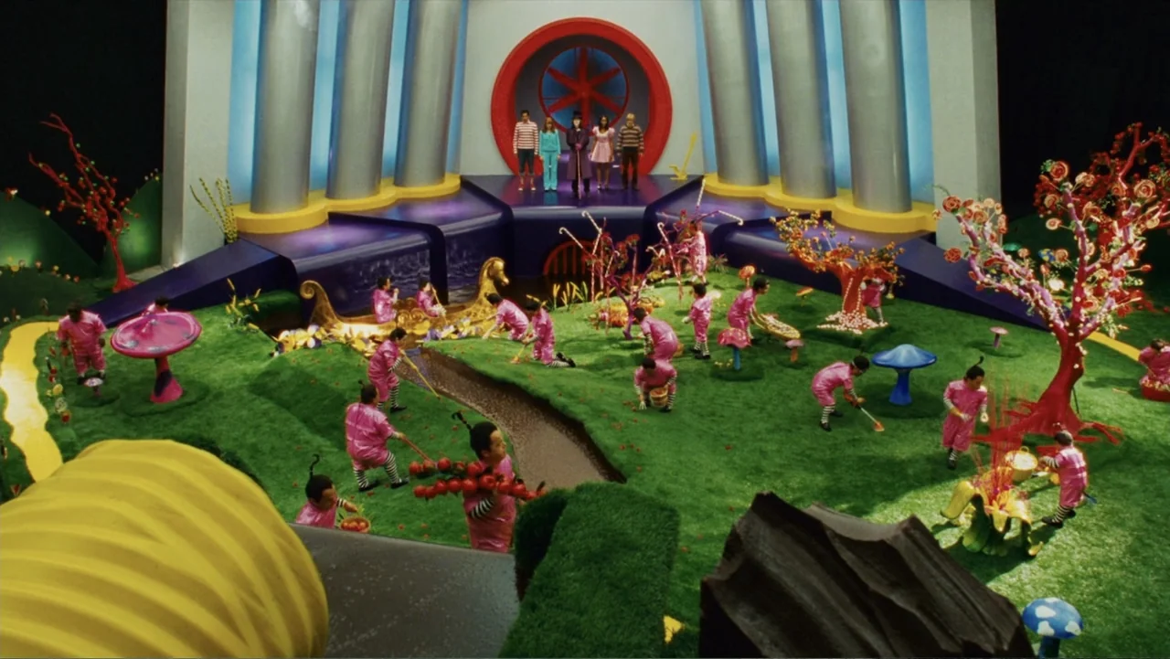 Epic Movie (2007) movie still: wide — A synthetic candy landscape features green artificial grass and a brown chocolate river. Numerous small…
