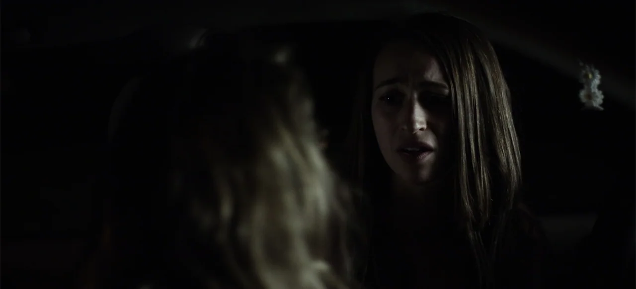 Hellbreeder (2004) movie still: closeup — The interior of a car at night with minimal light. A young woman with brown hair sits in the passenger…