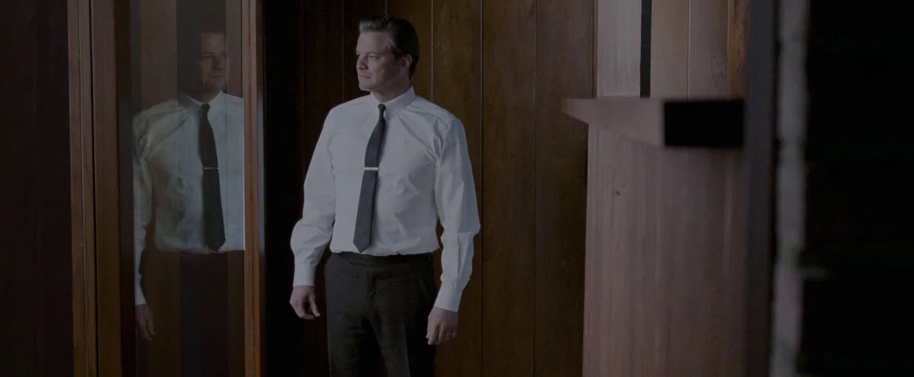 A Single Man (2009) movie still: medium — A narrow residential passage features dark vertical walnut-paneled walls and a tall vertical mirror. A…