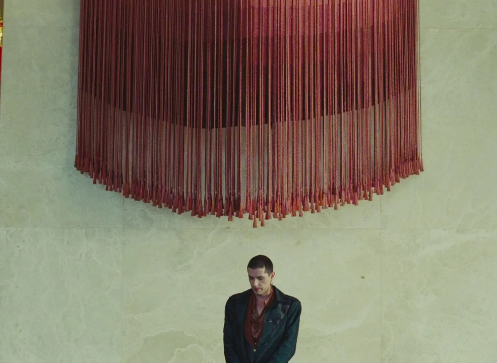 Laurence Anyways (2012) movie still: medium — A man stands before a large, multi-layered red rope fringe art piece on a marble wall. The minimalist…