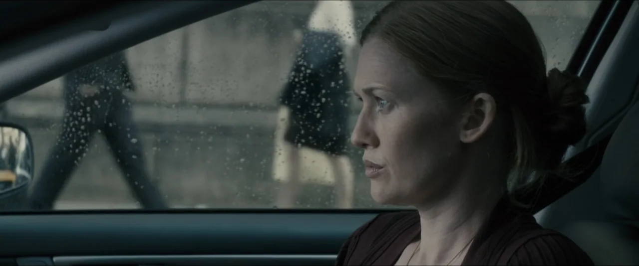 World War Z (2013) movie still: medium — The interior of a moving vehicle with rain droplets visible on the side window. A woman with light brown…