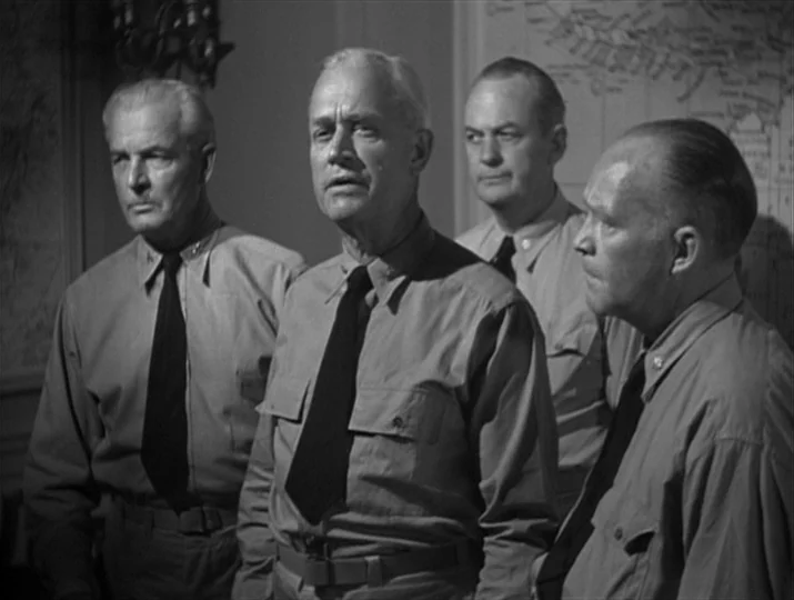 They Were Expendable (1945) movie still: medium — Four men in military uniforms stand in front of a wall-mounted map. They are gathered together,…