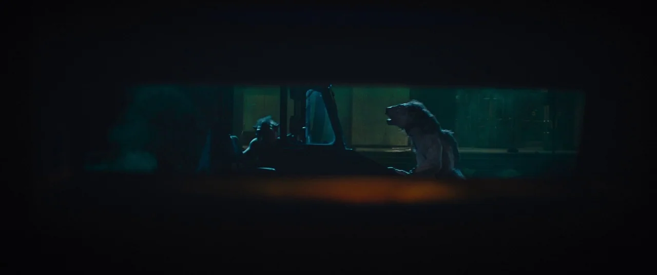 Sorry to Bother You (2018) movie still: wide — Two anthropomorphic werewolf figures sit inside a vehicle in a dark nighttime environment. A narrow…