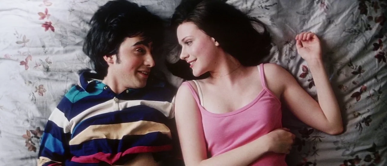 Pretty Persuasion (2005) movie still: medium — A man and a woman lie on a floral print bedspread. They gaze at each other while lying side-by-side…