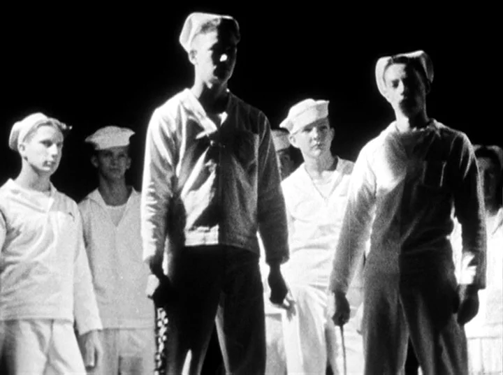 Fireworks (1947) movie still: medium — A group of men in naval uniforms stand side by side against a black void. They face forward in a single line…