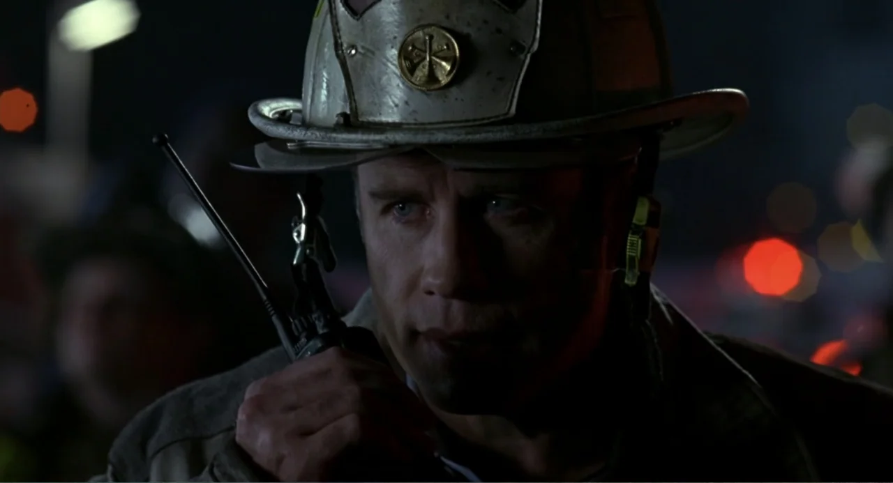 Ladder 49 (2004) movie still: closeup — An exterior night scene at an emergency site with blurred lights in the background. A man in a firefighter's…