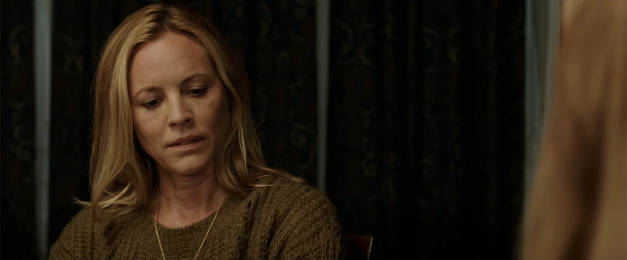 Lights Out (2016) movie still: closeup — A dimly lit indoor space with dark patterned curtains visible in the background. A woman in a knitted…