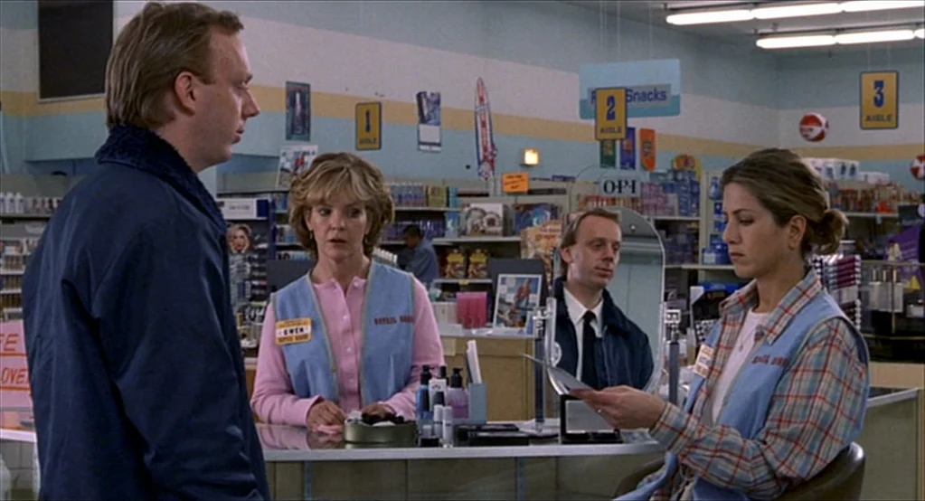 The Good Girl (2002) movie still: medium — A well-lit retail store interior features aisles marked with signs and a customer service counter. A…