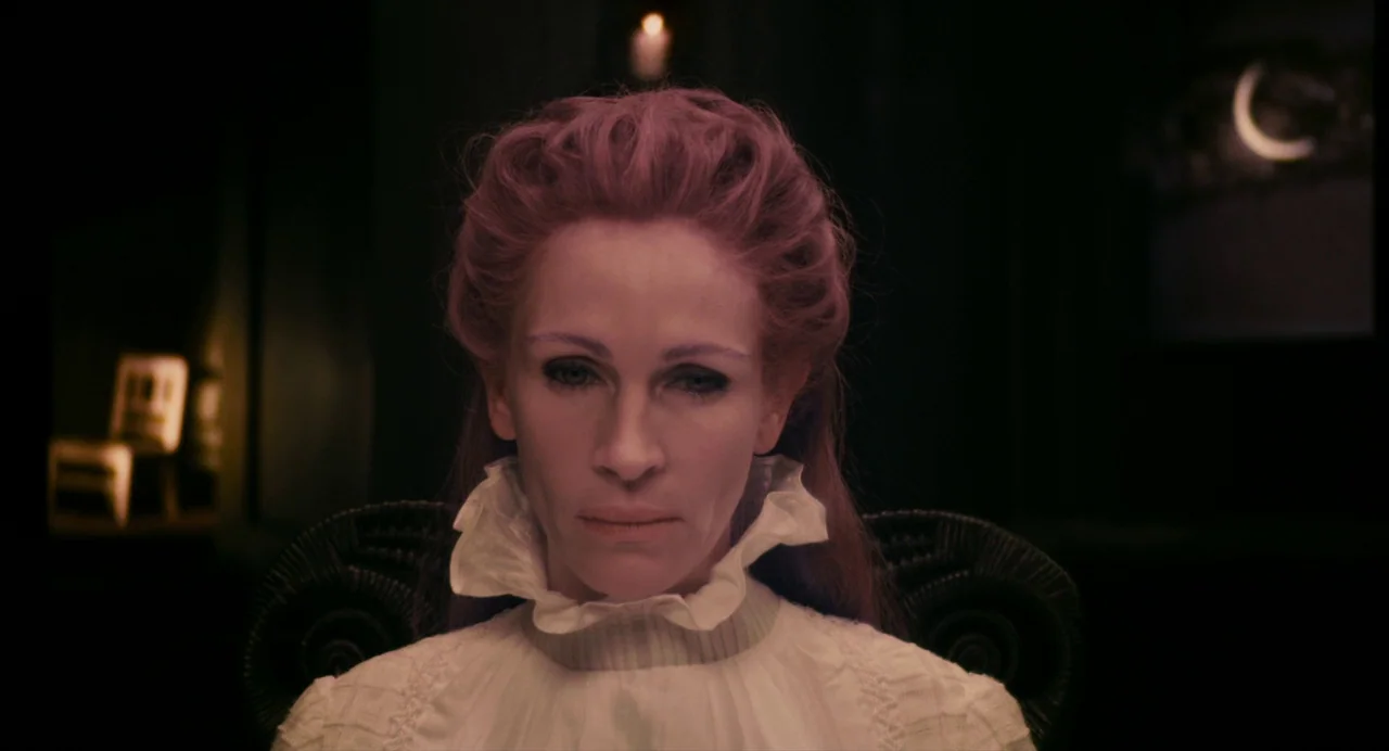 Mirror Mirror (2012) movie still: closeup — A dark, dimly lit room contains a single chair and a distant glowing candle. A woman with auburn hair…