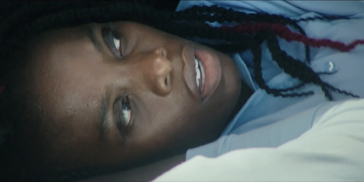 The Hunted (2024) movie still: closeup — A dimly visible interior space with minimal architectural detail surrounding the reclining subject. A woman…