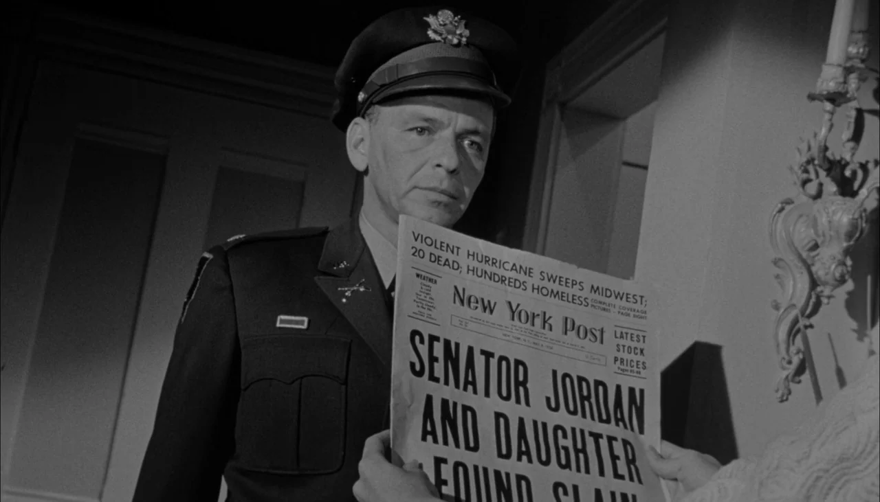 The Manchurian Candidate (1962) movie still: medium — An interior space with a wall-mounted light fixture near a door frame. A man in a military…