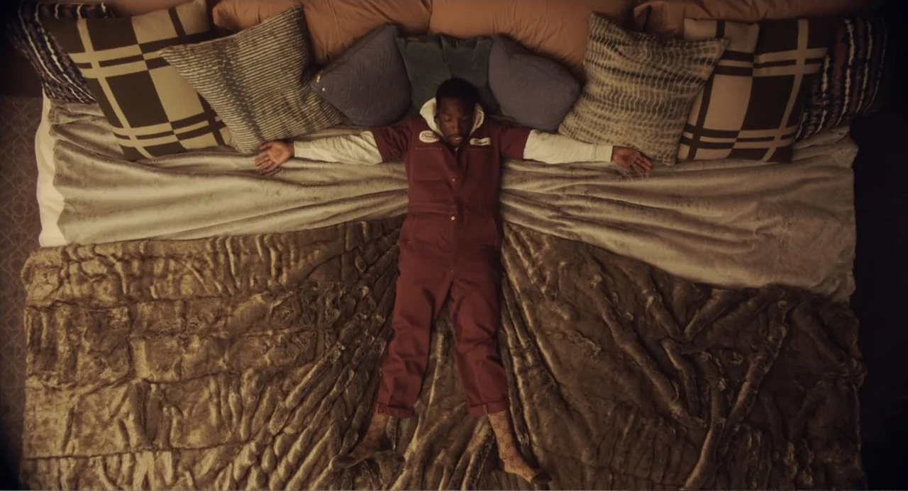 House Party (1990) movie still: fullbody — A man lies centered on a large bed covered with a faux fur blanket. He is positioned flat on his back…