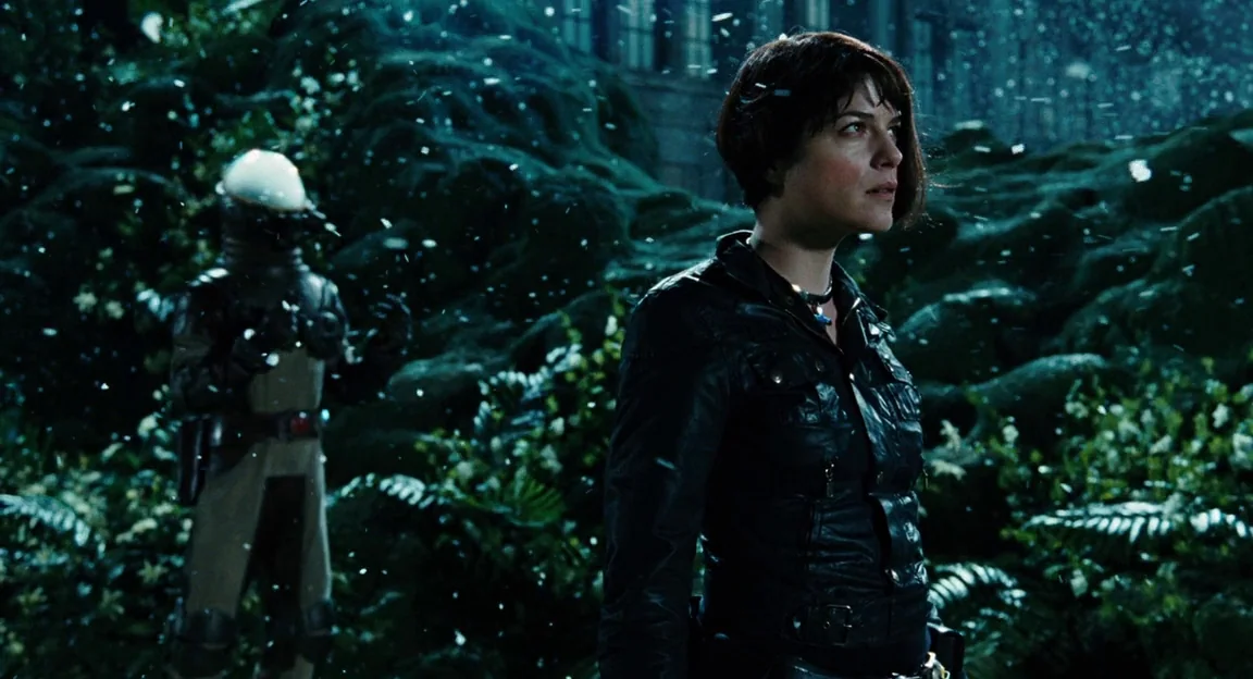 Hellboy II: The Golden Army (2008) movie still: medium — A dark, lush landscape is covered by falling snow at night. A woman in a leather jacket…