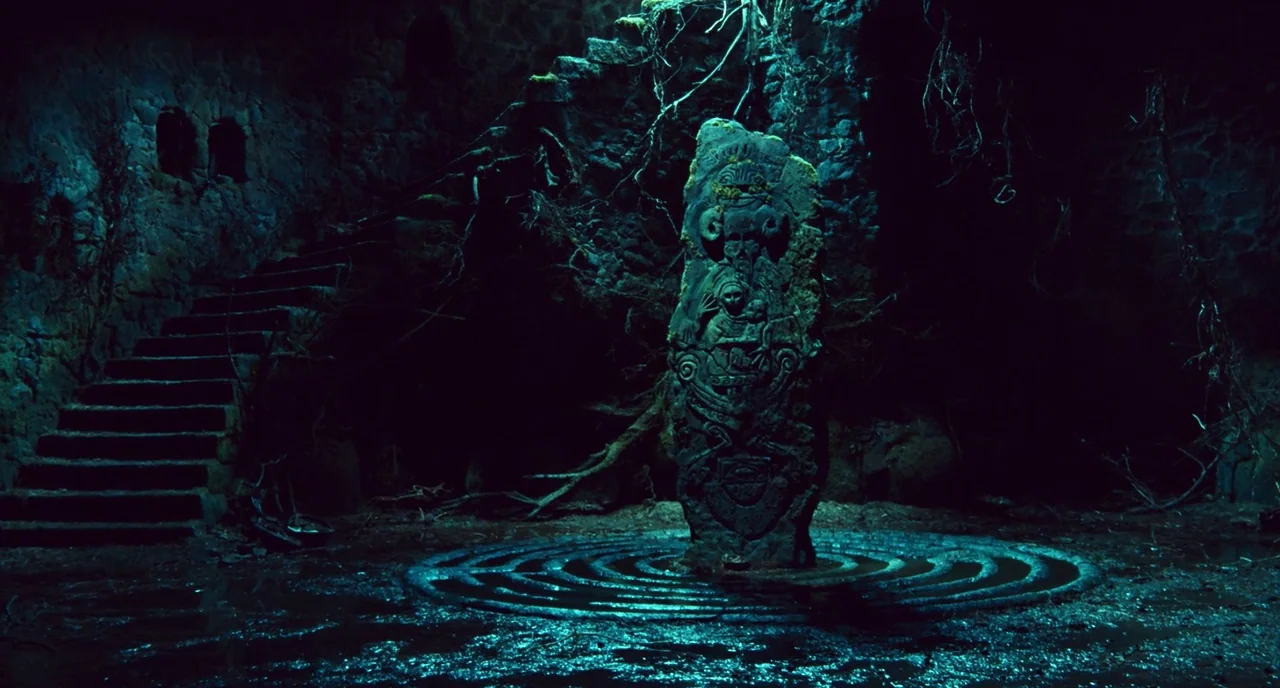 Pan’s Labyrinth (2006) movie still: establishing — A dark stone chamber features a central carved monolith surrounded by concentric circular…
