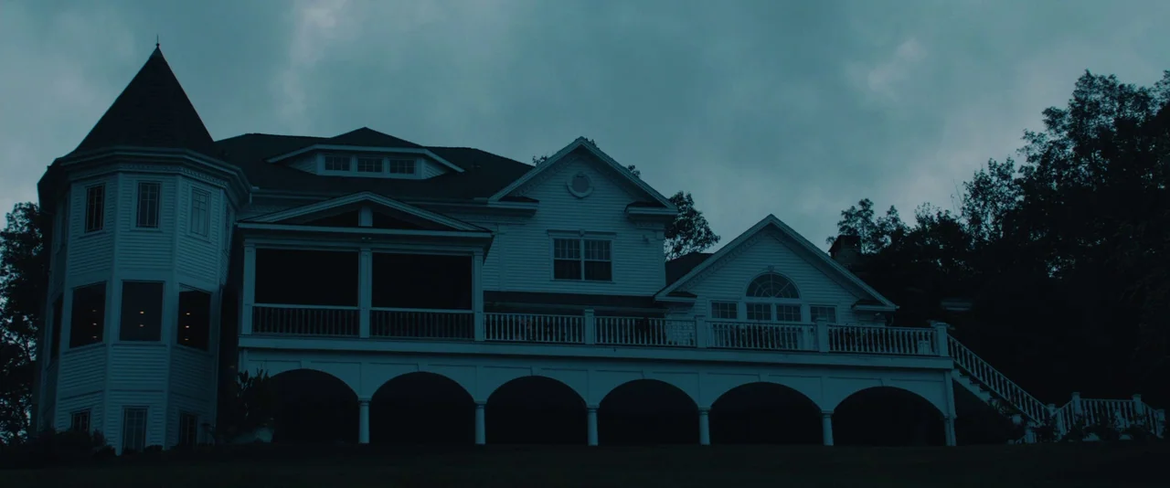 Kiss of the Damned (2012) movie still: establishing — A large two-story white house with a turret and multiple arched foundations at night. The…