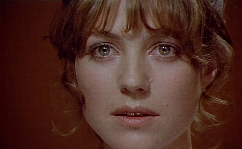 Two English Girls (1971) movie still: closeup — A close-up shot of a woman against a solid dark reddish-brown backdrop. The subject looks directly…