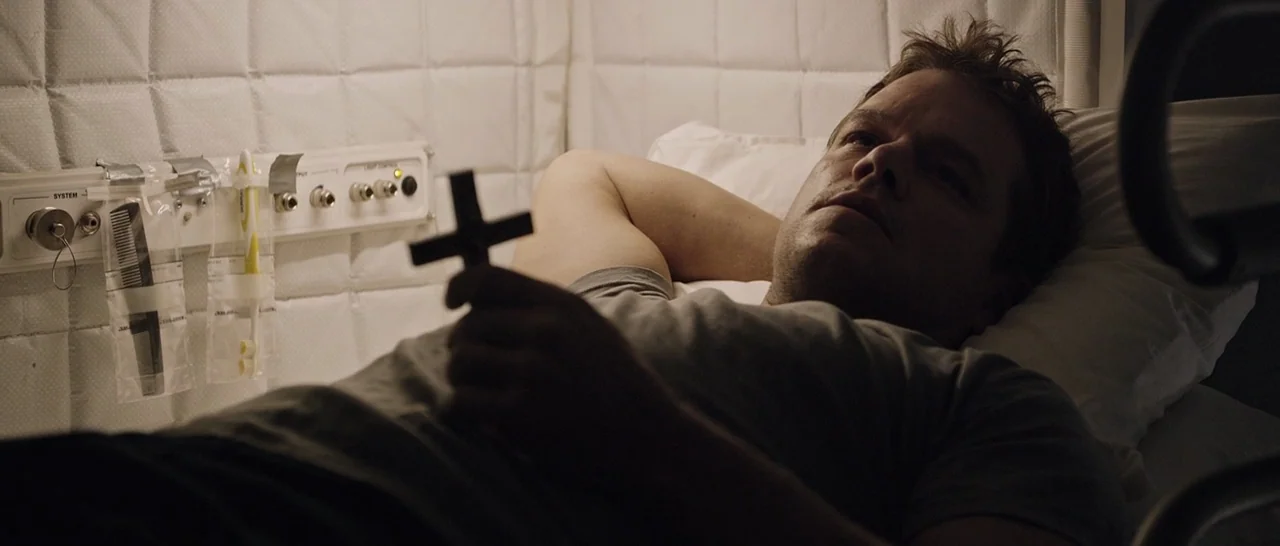 The Martian (2015) movie still: medium — A stark room with padded white walls and a utility panel containing basic toiletries. A man lies flat on…
