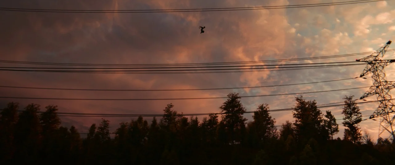 Spider-Man: No Way Home (2021) movie still: wide — A twilight sky filled with peach and grey clouds hangs over a treeline. A lone human silhouette…