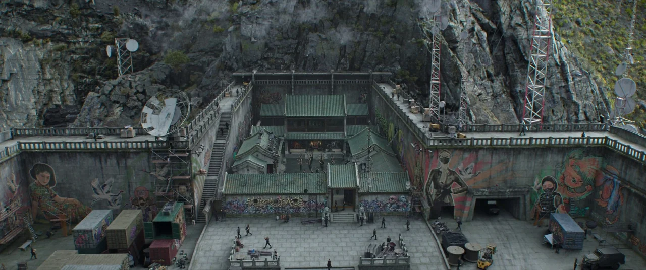Shang-Chi and the Legend of the Ten Rings (2021) movie still: establishing — A fortified rectangular compound with stone walls, satellite dishes,…