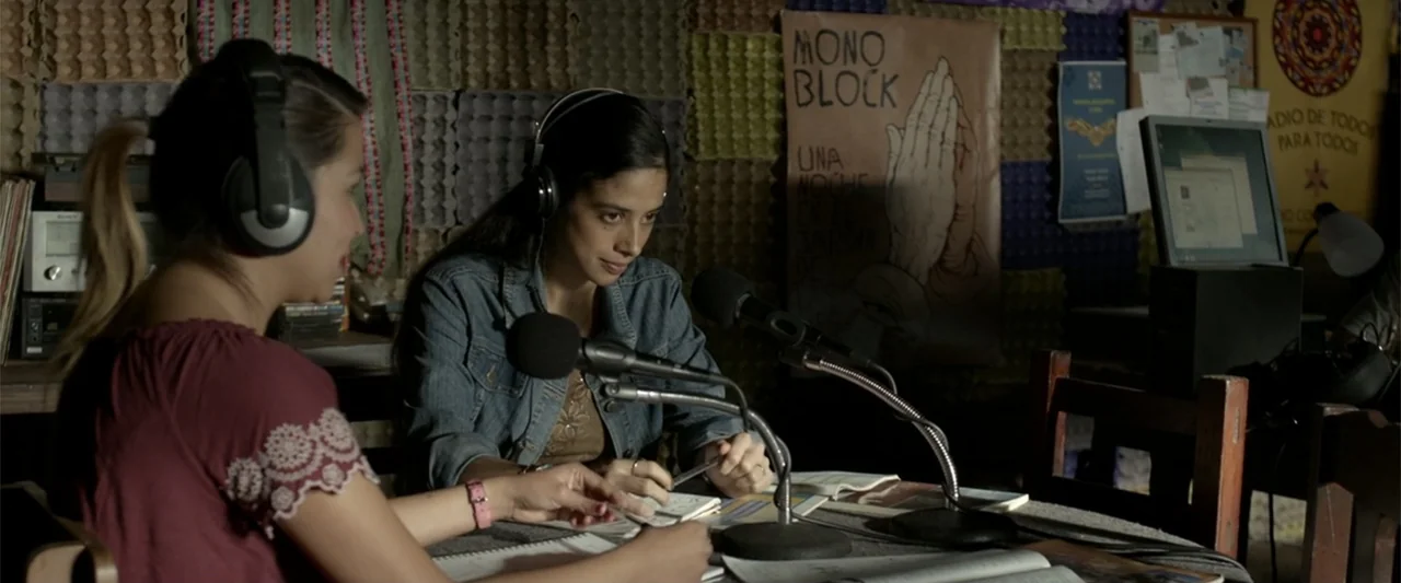 I Dream in Another Language (2017) movie still: medium — An interior radio broadcast room features acoustic foam-covered walls and a desk. Two young…
