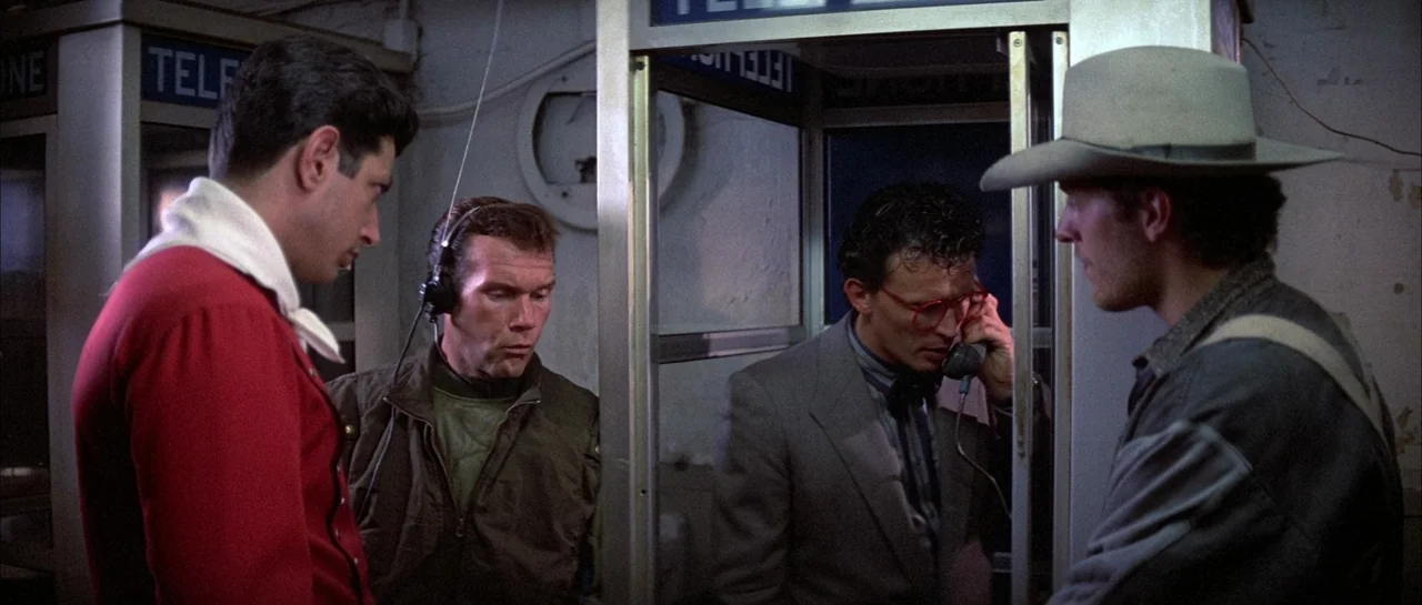 The Adventures of Buckaroo Banzai Across the 8th Dimension (1984) movie still: medium — Four men gather in a dimly lit area filled with vintage…