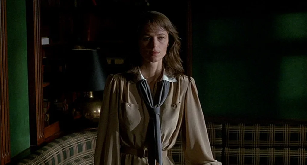 The Verdict (1982) movie still: medium — A dimly lit room features dark green paneled walls and a wooden bookshelf. A woman stands in the center of…