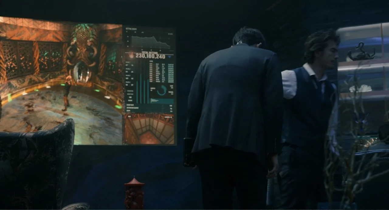 Knuckle Girl (2023) movie still: medium — A dark, modern surveillance room features a large digital screen showing complex data. Two men in formal…